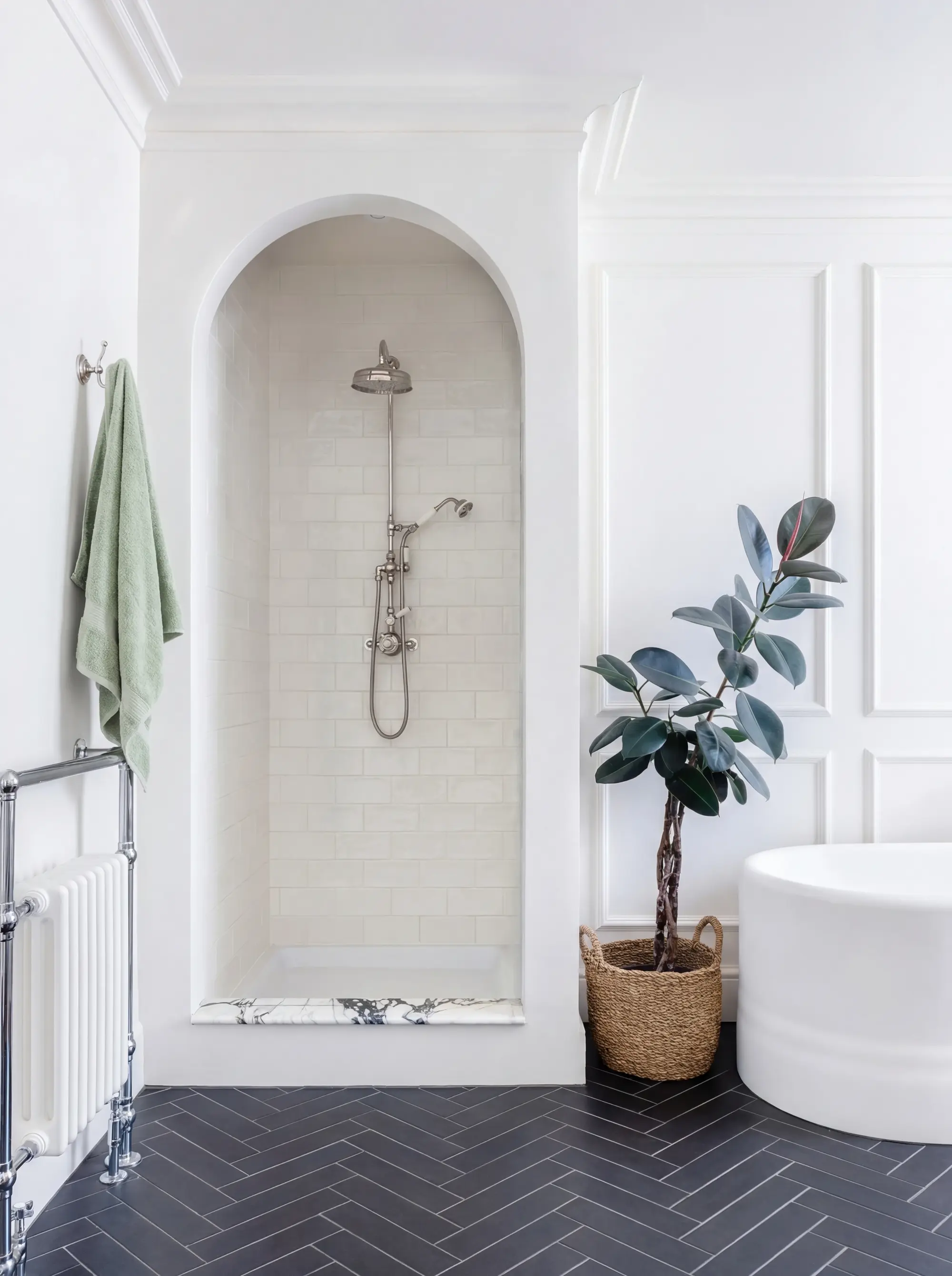 Bathroom with an arched shower alcove, freestanding bath and dark herringbone floor