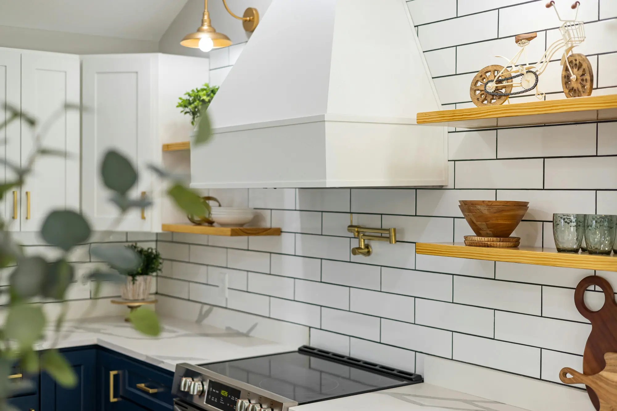 Kitchen with white metro tiles, open oak shelves and brass fittings