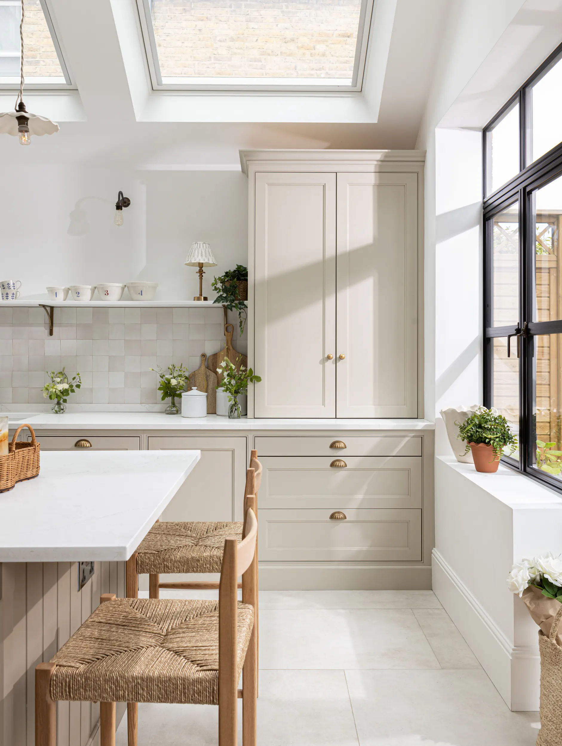 Cream shaker kitchen under a skylight with rush-seat stools – Chiswick renovation