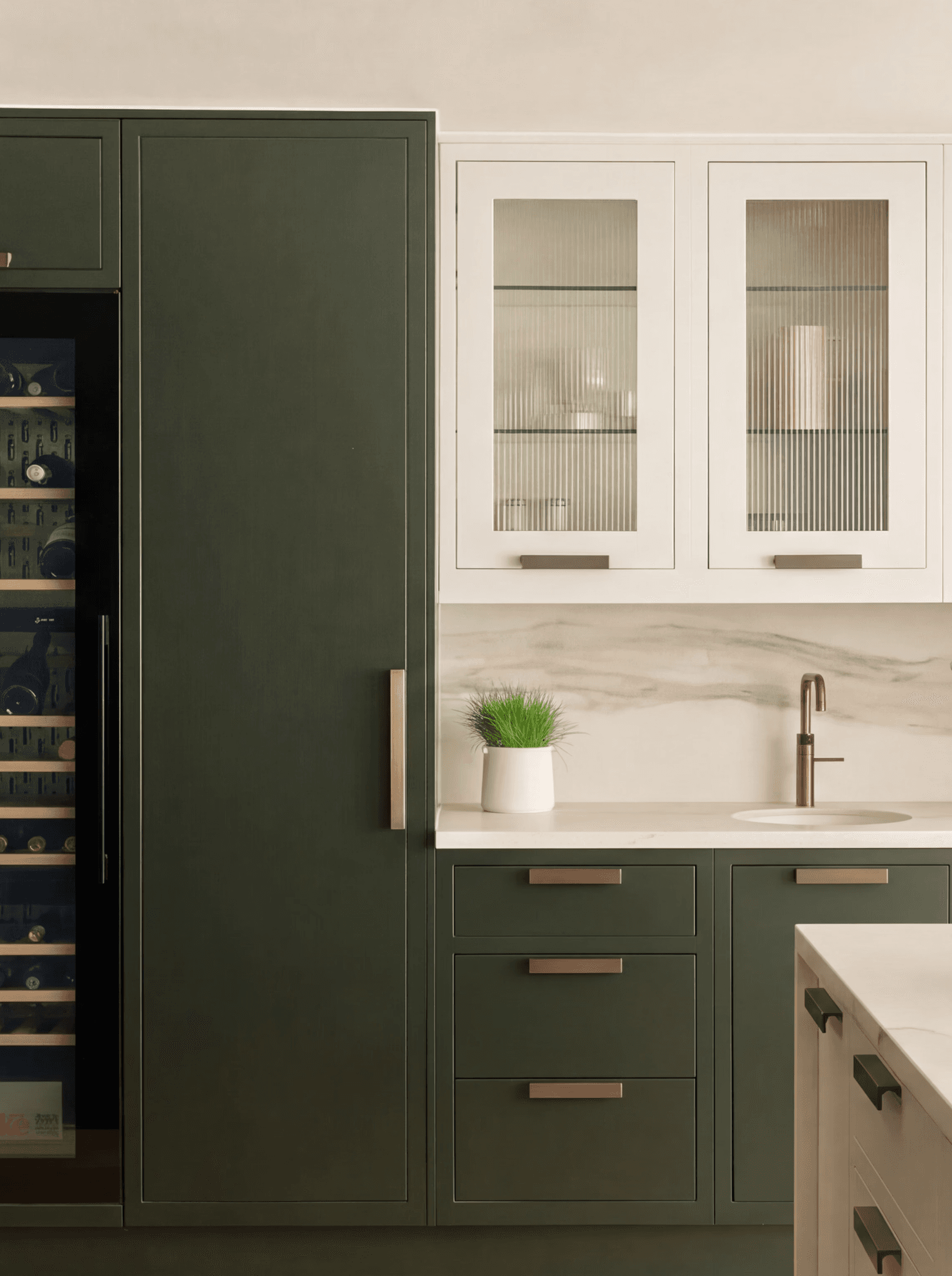 Dark green tall kitchen units with glass-fronted wall cabinets and integrated wine cooler