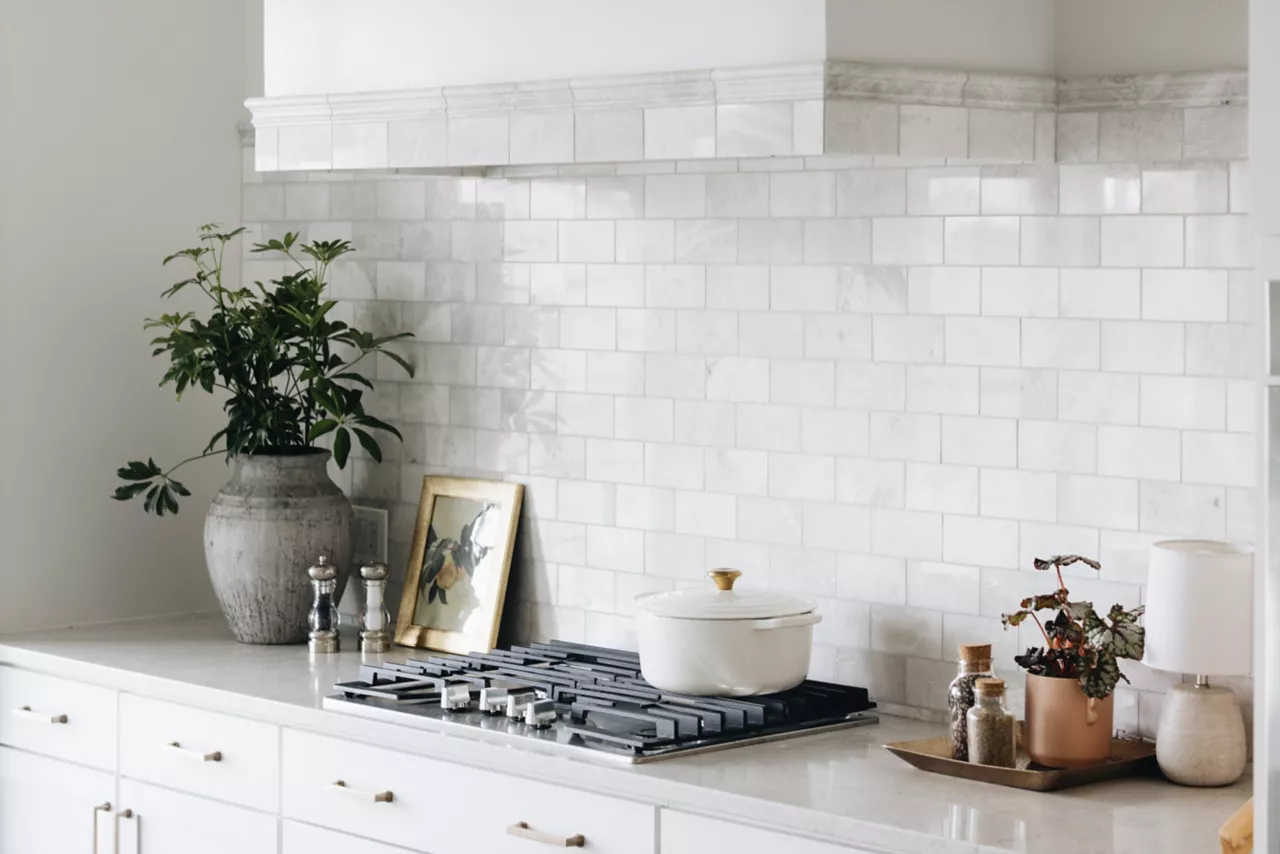 White kitchen with a metro tile splashback, gas hob and extractor hood