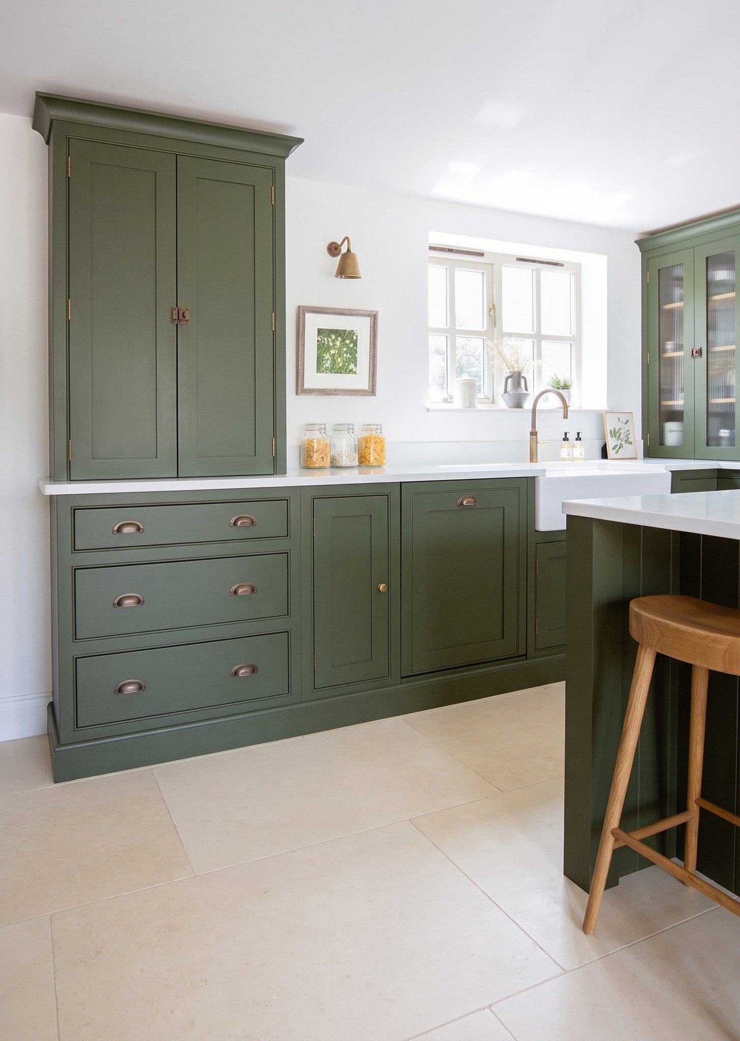 Green shaker kitchen units with a timber bar stool at the island