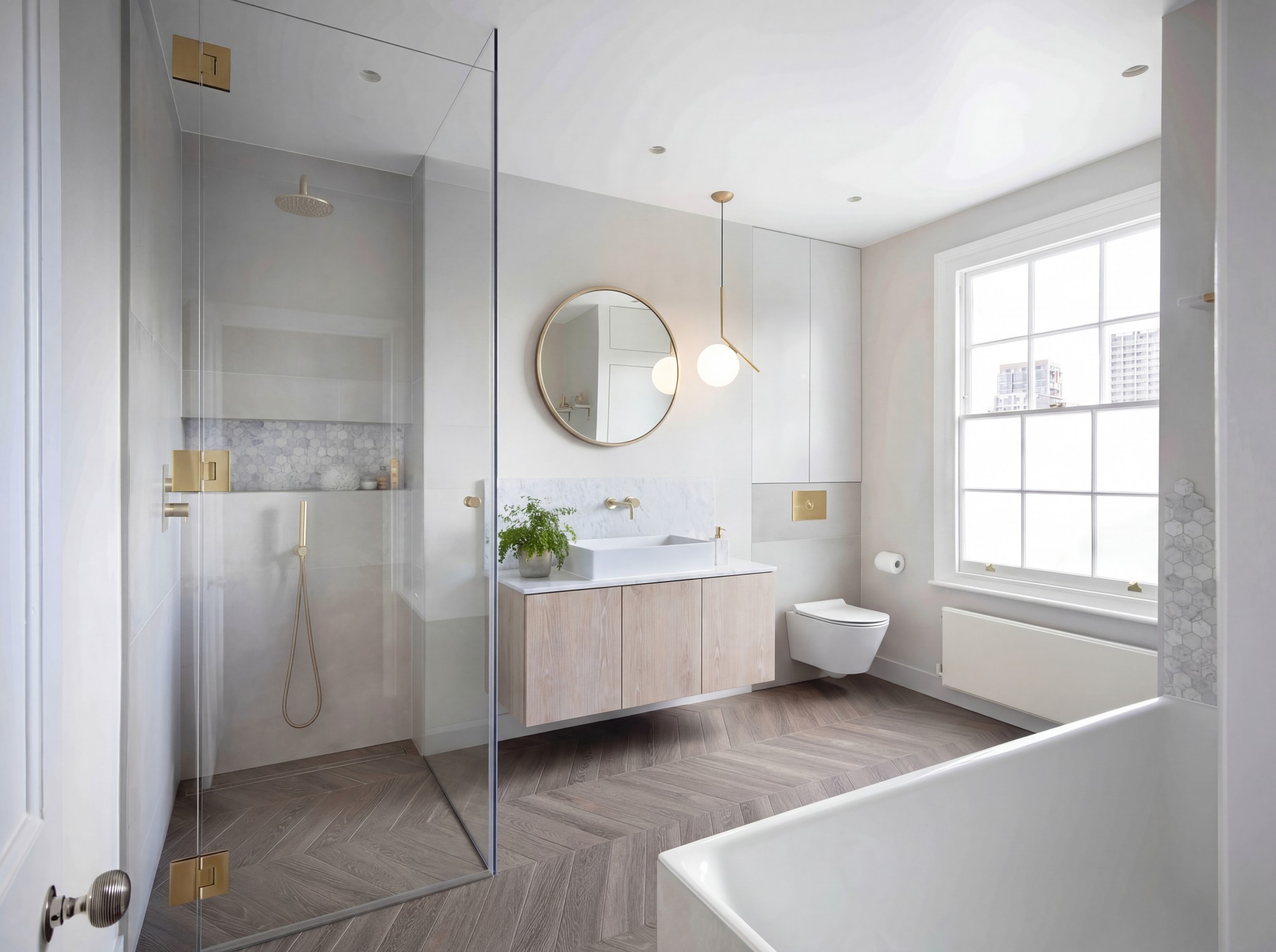 Bathroom with a walk-in shower, oak floating vanity, round mirror and herringbone floor