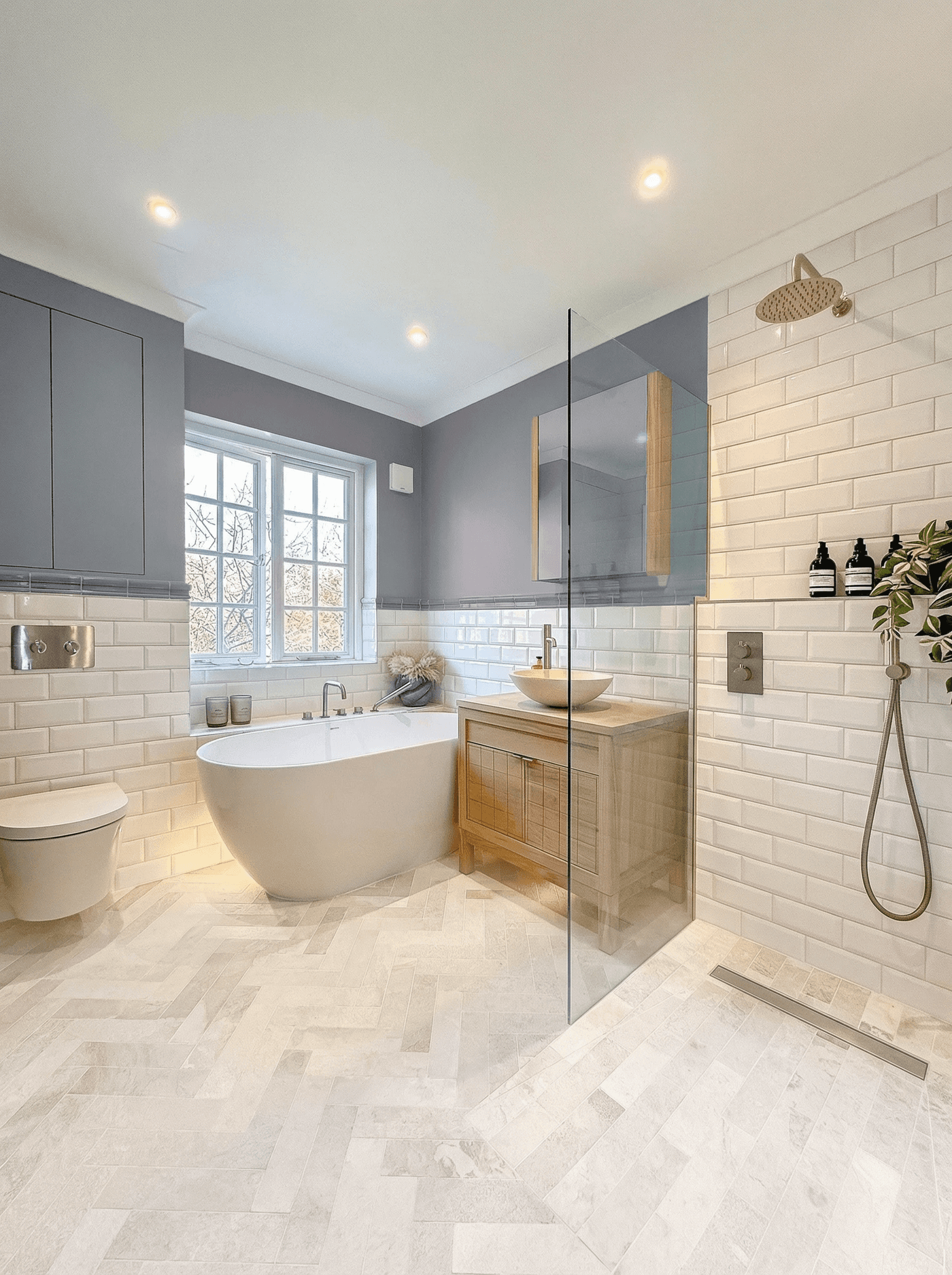 Bathroom with a freestanding bath, wooden vanity, walk-in shower and herringbone marble floor